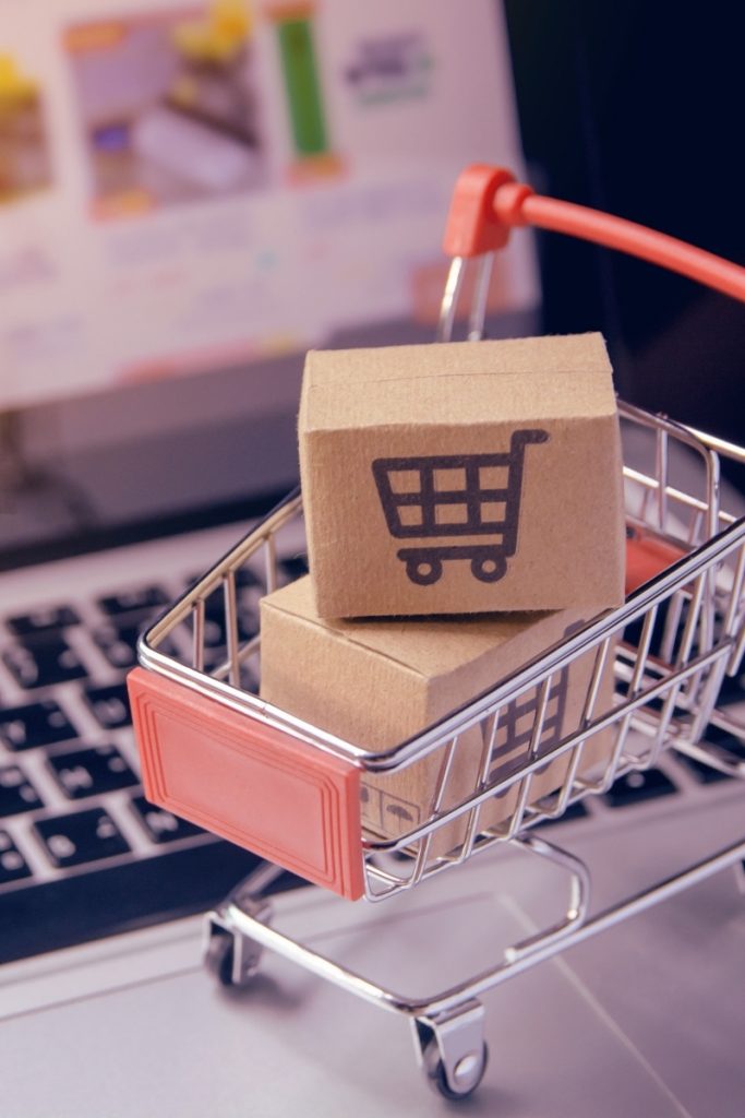 Mini shopping cart with parcels on a laptop keyboard for Greenwich e commerce