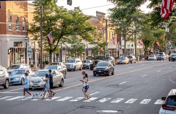 A shopping street with pedestrians, cars and storefronts